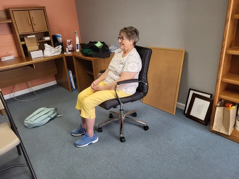 A woman sitting in an office chair with her feet on the desk.