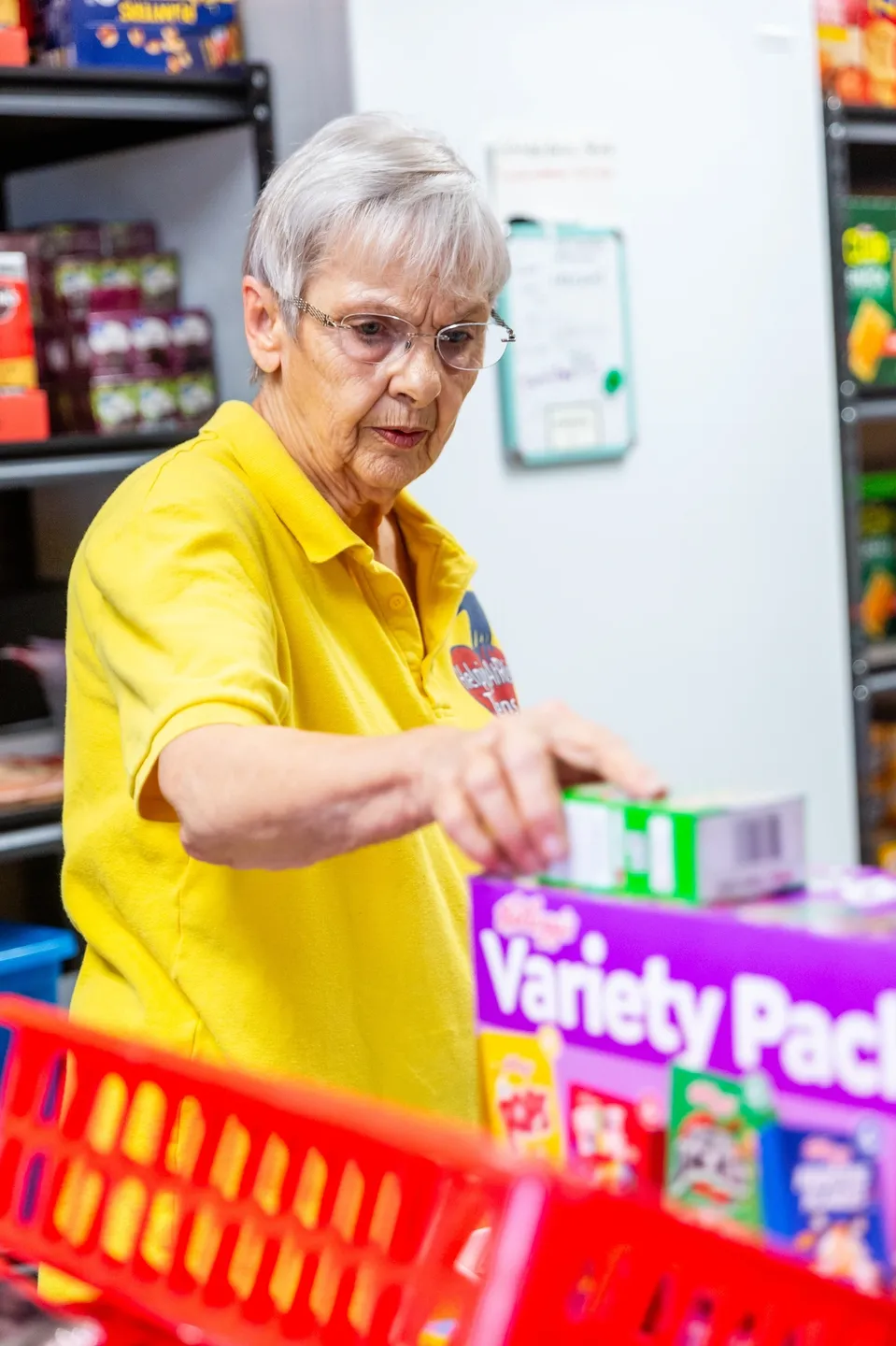 A woman in yellow shirt putting boxes of food on top.