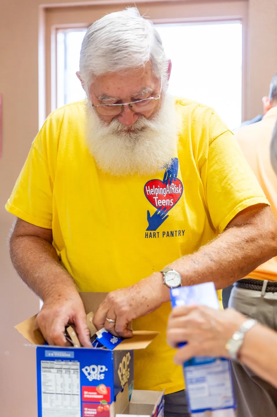 A man in yellow shirt cutting paper with scissors.