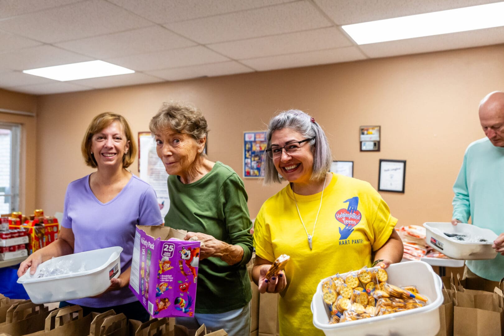 Three women are holding boxes of food and smiling.