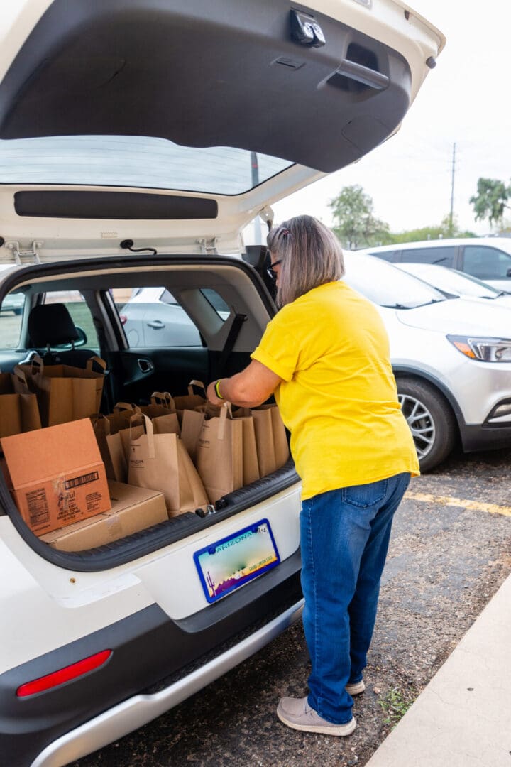 A woman loading groceries into the back of her car.