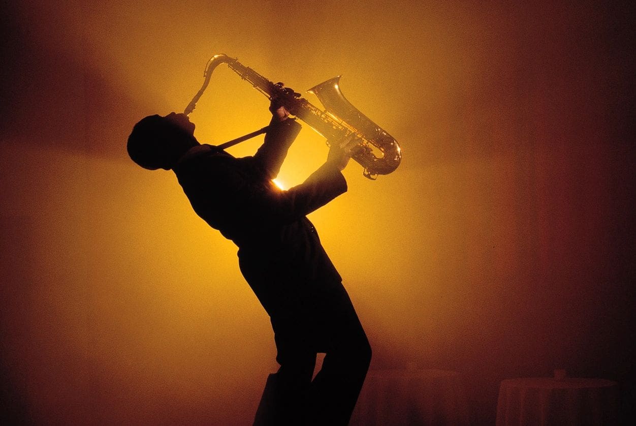 a man playing the trumpet in the dark light